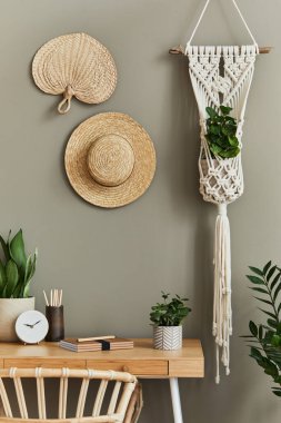 Şık koltuğu, ahşap masası, ev bitkileri, kaktüsü, rattan dekorasyonu, makrome ve saati olan boho oturma odasının iç tasarımı. Botanik bürosu. Şablon.