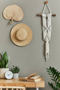 Şık koltuğu, ahşap masası, ev bitkileri, kaktüsü, rattan dekorasyonu, makrome ve saati olan boho oturma odasının iç tasarımı. Botanik bürosu. Şablon.