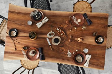 Ahşap ceviz masası, retro sandalyeler, sofra takımı, tabaklar, masa örtüsü, çaydanlık, yemek, dekorasyon ve zarif aksesuarları olan şık bir iç dizayn. Beton zemin. Şablon. Üst görünüm.