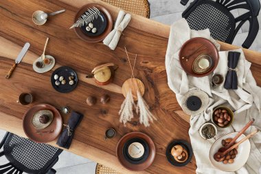 Ahşap ceviz masası, retro sandalyeler, sofra takımı, tabaklar, masa örtüsü, çaydanlık, yemek, dekorasyon ve zarif aksesuarları olan şık bir iç dizayn. Beton zemin. Şablon. Üst görünüm.