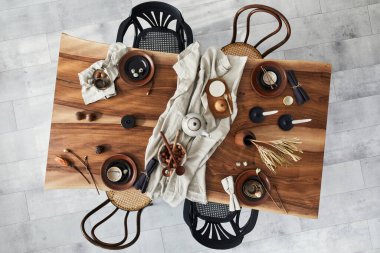 Ahşap ceviz masası, retro sandalyeler, sofra takımı, tabaklar, masa örtüsü, çaydanlık, yemek, dekorasyon ve zarif aksesuarları olan şık bir iç dizayn. Beton zemin. Şablon. Üst görünüm.