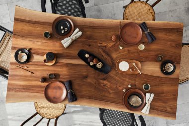 Ahşap ceviz masası, retro sandalyeler, sofra takımı, tabaklar, masa örtüsü, çaydanlık, yemek, dekorasyon ve zarif aksesuarları olan şık bir iç dizayn. Beton zemin. Şablon. Üst görünüm.