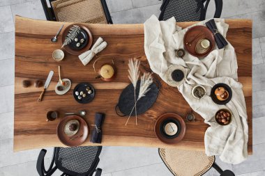 Ahşap ceviz masası, retro sandalyeler, sofra takımı, tabaklar, masa örtüsü, çaydanlık, yemek, dekorasyon ve zarif aksesuarları olan şık bir iç dizayn. Beton zemin. Şablon. Üst görünüm.