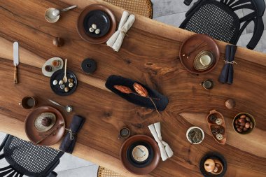 Ahşap ceviz masası, retro sandalyeler, sofra takımı, tabaklar, masa örtüsü, çaydanlık, yemek, dekorasyon ve zarif aksesuarları olan şık bir iç dizayn. Beton zemin. Şablon. Üst görünüm.