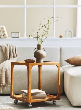 Oturma odasının iç kısmının nötr kanepe, ahşap yan masa, vazoda kurumuş çiçek, yastık, pencere, dekorasyon ve ev dekorasyonunda zarif kişisel aksesuarlar ile minimalist kompozisyonu. Şablon