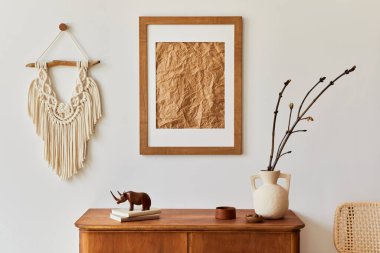 Kahverengi resim çerçevesi, bitki, retro koltuk, kurumuş tropikal yaprak, dekorasyon ve şık ev dekorasyonuyla süslenmiş kişisel aksesuarları olan minimalist oturma odası kompozisyonu. Şablon.