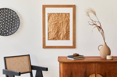 Kahverengi resim çerçevesi, bitki, retro koltuk, kurumuş tropikal yaprak, dekorasyon ve şık ev dekorasyonuyla süslenmiş kişisel aksesuarları olan minimalist oturma odası kompozisyonu. Şablon.