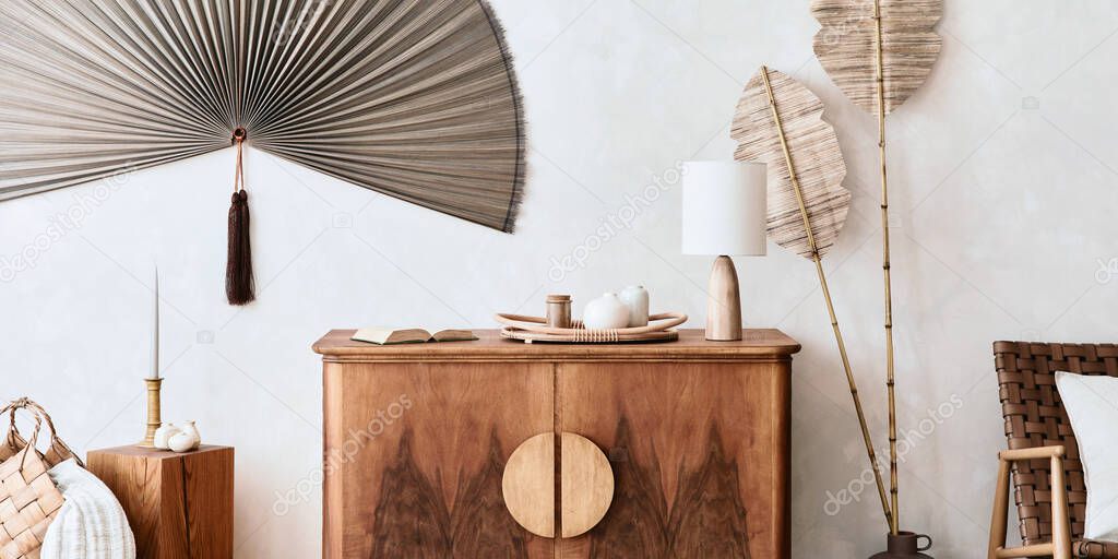 Japandi concept of living room interior with design wooden commode, table lamp, tropical dried leaf in vase, cubes, decoration, japanese fan and elegant personal accessories in home decor. Template.