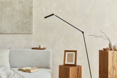 Poster çerçevesi, gri zarif kanepe, tahta küpler, modern lamba ve kişisel aksesuarlarla dekore edilmiş modern bir oturma odası kompozisyonu. Tarafsız renkler. Şablon. 