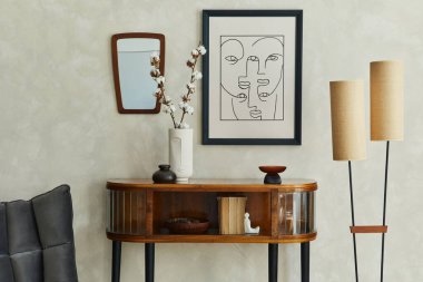 Afiş çerçevesi, ahşap tuvalet, gri sandalye, lamba, ayna ve zarif kişisel aksesuarlarla dekore edilmiş yaratıcı oturma odasının şık kompozisyonu. Tarafsız bej duvar. Şablon.