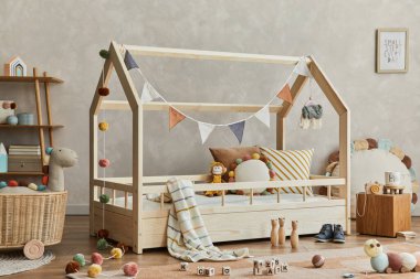 Ahşap yatak, raf, peluş ve ahşap oyuncaklar ve tekstil asma süslemeleriyle İskandinav çocuk odasının iç kısmının şık kompozisyonu. Tarafsız yaratıcı duvar, yerde halı. Şablon. 