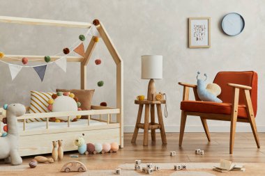 İskandinav çocuk odasının içinde ahşap yatak, kırmızı koltuk, peluş ve ahşap oyuncaklar ve tekstil asma süslemeleri olan şık bir kompozisyon. Yaratıcı duvar, yerde halı. Şablon.