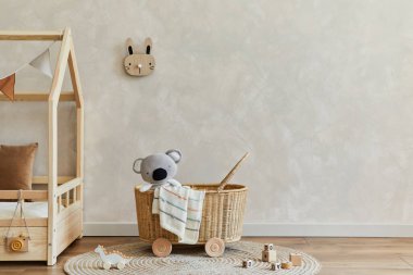 Şık İskandinav çocuk odası iç dekorasyonu yatak, rattan sepeti, peluş ve ahşap oyuncaklar ve tekstil asma süslemeleri. Yaratıcı duvar, yerde halı. Uzayı kopyala Şablon.