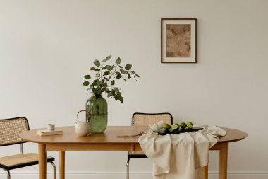 Minimalist düzeneği olan parlak bir iç mekan. Tarafsız keten üzerine yeşillik, çaydanlık ve limon serpiştirilmiş bir yemek masası. İskandinav ve Japon tasarımı etkiler.