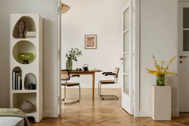 Minimalist yemek odası, orta çağ modern sandalyeler, ahşap masa ve sarı bahar çiçekli yeşil vazo. Tarafsız tonlar ve temiz stil doğal dokuları vurgular.