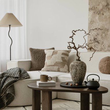 Yumuşak yastıklı, seramik vazosu olan rahat bir oturma odası ve işlenmemiş sanatsal bir arkaplana karşı şekillendirilmiş kurumuş dallar..