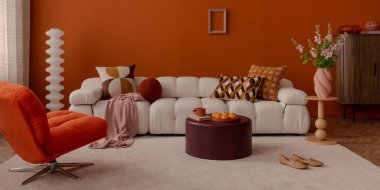 Sıcak tonlarda kavisli kanepe ve geometrik minderlerle modern iç mekan..