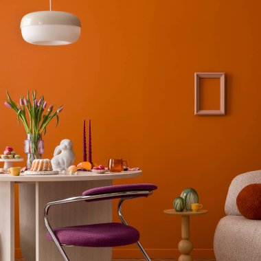 Makaronlar, mumlar, seramik tavşanlar ve sıcak tonda iç mekânda çiçeklerle süslü Paskalya sofrası..