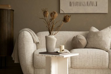 İç tarafında bir kanepe, masa dekorasyonu ve bej duvarlar var. Sıcak, nötr bir renk paleti. Yaşam tarzı, ev dekorasyonu, huzur ve rahatlama için kullanılıyor.