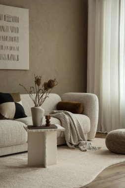 İç tarafında bir kanepe, masa dekorasyonu ve bej duvarlar var. Sıcak, nötr bir renk paleti. Yaşam tarzı, ev dekorasyonu, huzur ve rahatlama için kullanılıyor.