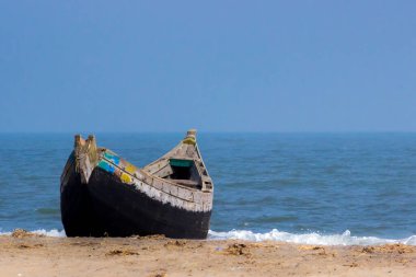 Arka planda mavi gökyüzü olan deniz kıyısındaki bir tekne manzarası.