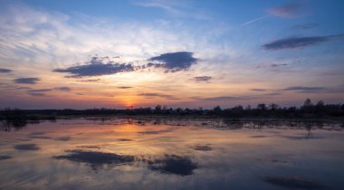 Günbatımı nehri sakin manzarası. Akşamları nehir kenarında. Günbatımı gökyüzü nehirde yansıyor..