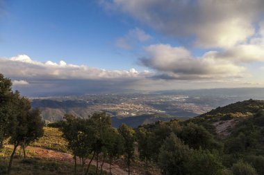 Montserrat dağlarının güzel bir bahar günü havadan görünüşü, Katalonya, İspanya. Dağların üzerinde dramatik bir gökyüzü. Güneş ışığı bulutların arasından düşer yeryüzüne ve dağlara.