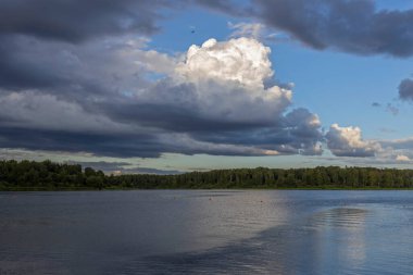Akşamları nehrin üzerinde bulutlu bir gökyüzü. Bulutları ve nehri olan resim gibi bir manzara..