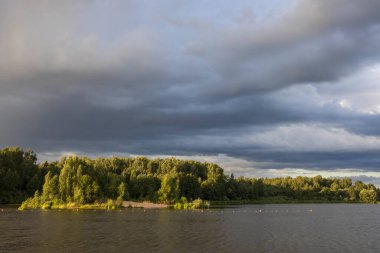 Akşamları nehrin üzerinde bulutlu bir gökyüzü. Bulutları ve nehri olan resim gibi bir manzara..