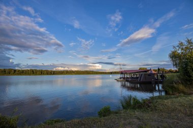 Akşamları nehrin üzerinde bulutlu bir gökyüzü. Bulutları ve nehri olan resim gibi bir manzara..