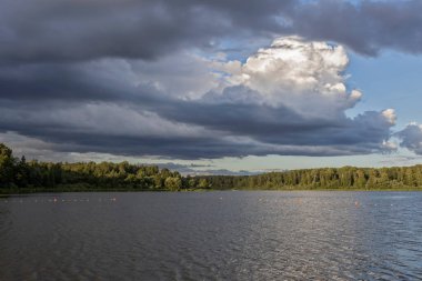 Akşamları nehrin üzerinde bulutlu bir gökyüzü. Bulutları ve nehri olan resim gibi bir manzara..