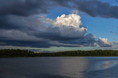 Akşamları nehrin üzerinde bulutlu bir gökyüzü. Bulutları ve nehri olan resim gibi bir manzara..
