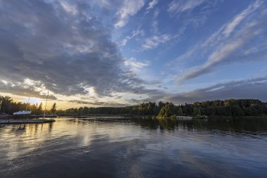 Bulutlu nehirde gün batımını hayal et. Akşamki dramatik gökyüzü nehire yansıyor.