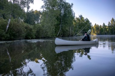 Bir adam gölde bir kanoyla yelken açıyor. kano.
