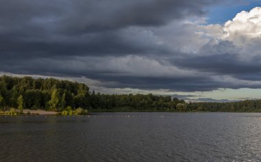 Akşamları nehrin üzerinde bulutlu bir gökyüzü. Bulutları ve nehri olan resim gibi bir manzara..