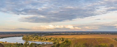 Akşamları renkli manzara, tepeleri ve nehri olan altın bulutları olan muhteşem mavi gökyüzü. Doğanın büyülü anı. 