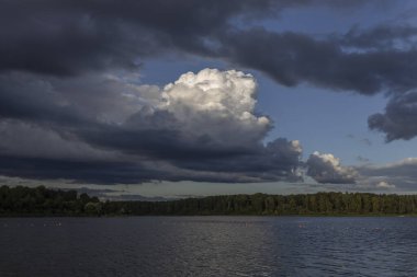Akşamları nehrin üzerinde bulutlu bir gökyüzü. Bulutları ve nehri olan resim gibi bir manzara..