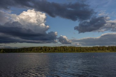 Akşamları nehrin üzerinde bulutlu bir gökyüzü. Bulutları ve nehri olan resim gibi bir manzara..