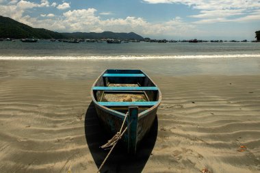 Sahilde mavi gökyüzü ve arka planda deniz tekneleri olan balıkçı teknesi.