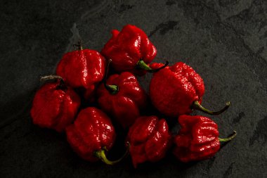 Koyu arkaplanda Habanero biberleri, kırsal masada olgun kırmızı biberler, acı habanero biberleri. Metin için boşluk