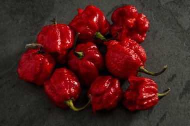 Koyu arkaplanda Habanero biberleri, kırsal masada olgun kırmızı, acılı habanero biberleri