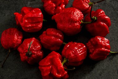 Koyu arkaplanda Habanero biberleri, kırsal masada olgun kırmızı, acılı habanero biberleri