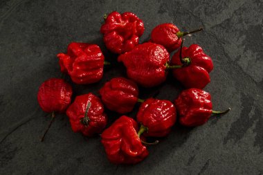 Koyu arkaplanda Habanero biberleri, kırsal masada olgun kırmızı, acılı habanero biberleri