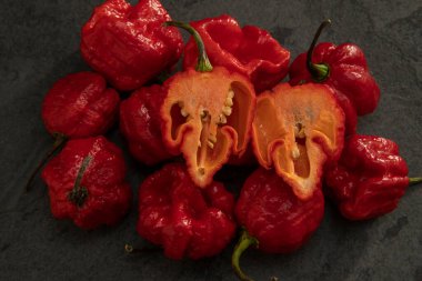 Koyu arkaplanda Habanero biberleri, kırsal masada olgun kırmızı, acılı habanero biberleri