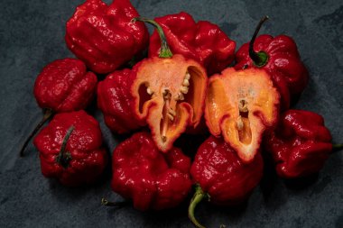 Koyu arkaplanda Habanero biberleri, kırsal masada olgun kırmızı, acılı habanero biberleri