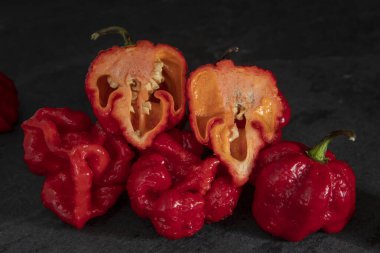 Koyu arkaplanda Habanero biberleri, kırsal masada olgun kırmızı, acılı habanero biberleri