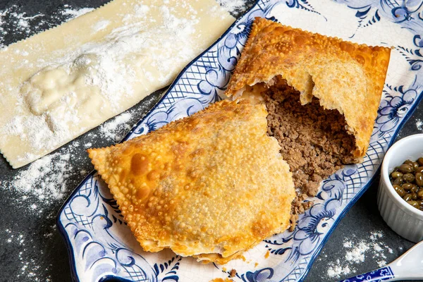 Brazilian food. Pastel, pastry in English, typical dish of the street fairs of southeastern Brazil, fried and raw, stuffed with meat, in crockery decorated in blue with pepper