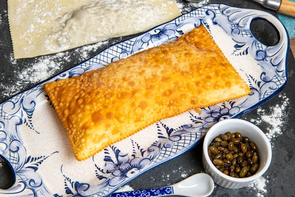 Brazilian food. Pastel, pastry in English, typical dish of the street fairs of southeastern Brazil, fried and raw, stuffed with cheese and meat, in crockery decorated in blue with pepper