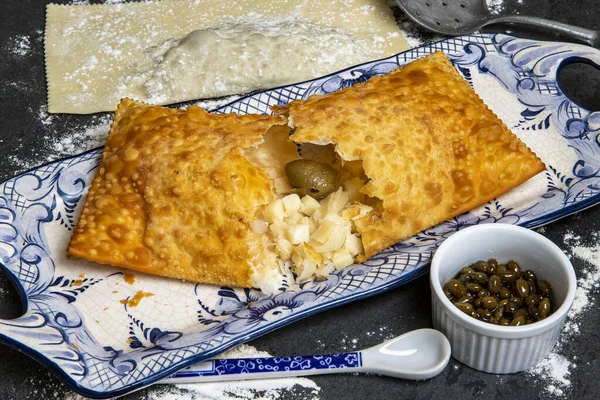 Brazilian food. Pastel, pastry in English, typical dish of the street fairs of southeastern Brazil, fried and stuffed with palm heart in crockery decorated in blue with pepper
