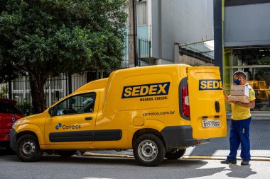 Sao Paulo, Brezilya Nisan 24 - 2021: Brezilya Postanesinden lojistik minibüs. İşçi, Brezilya 'da anti-covid maskeli sedex posta dağıtıyor. Brezilya hükümeti kamu kuruluşunun özelleştirildiğini duyurdu